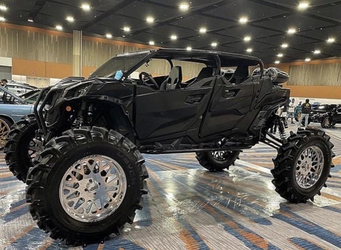 Lifted black side-by-side off-road vehicle on display indoors
